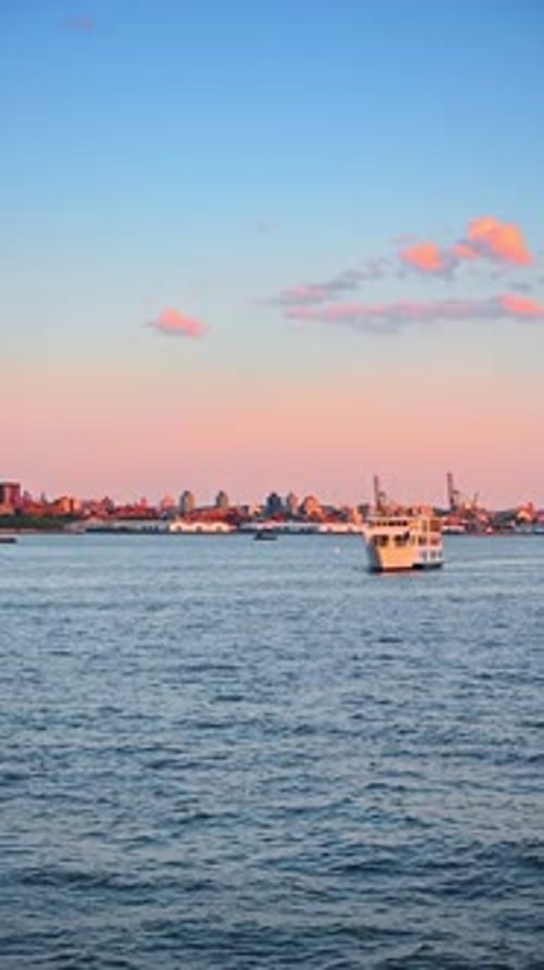 Sunset view of the East River from the riverscape. A modern cruise boat approaches the camera.