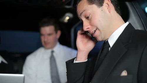 Corporate Group in Limousine Discussing Business on Phone
