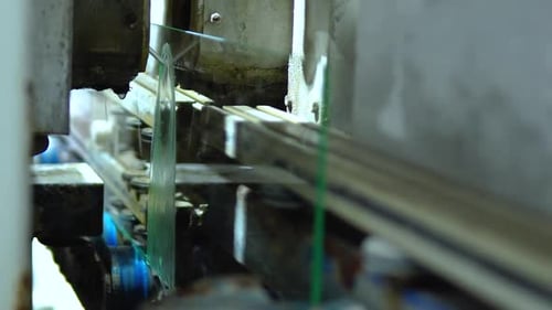 Láminas de vidrio que pasan por máquinas perforadoras automáticas durante su procesamiento en la fábrica de vidrio