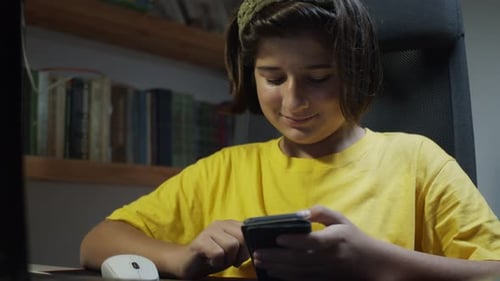 Teenager Typing on Smartphone at Desk Indoors