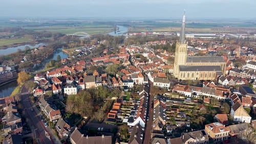 Aerial view of European town with red roofed buildings winding river bridges central church spire