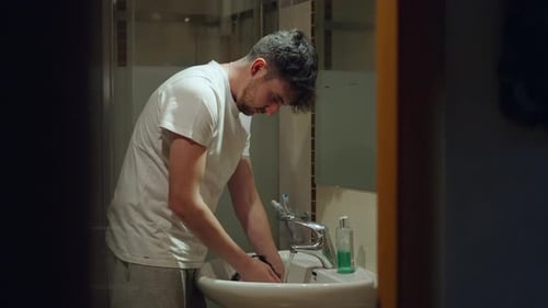 Young Adult Man Washing a Dog in Sink