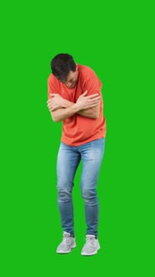 Homme frissonnant debout dans un studio avec les bras croisés