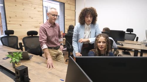 Équipe commerciale ayant une réunion informelle analysant les données sur un écran d'ordinateur