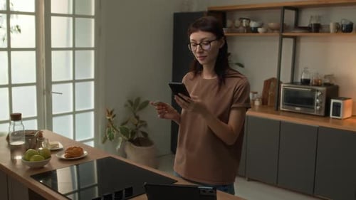 Young Woman Using Phone and Credit Card at Home