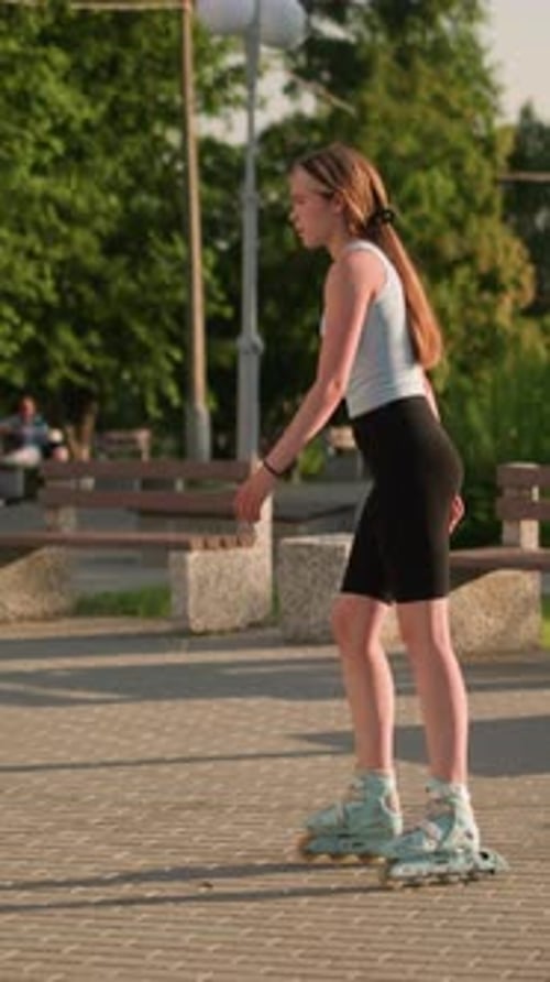 Woman Skating Slowly in Park with Benches and Sunlit Greenery in Background