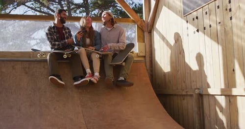 Video of happy diverse female and male skateboarders in skate park