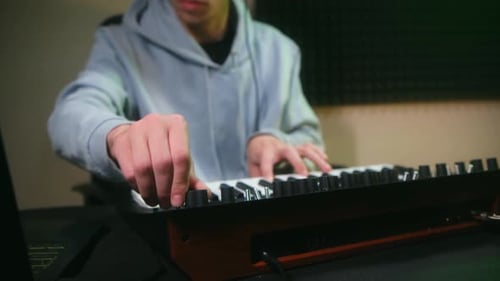 Man Adjusting Synthesizer in Studio with Headphones On