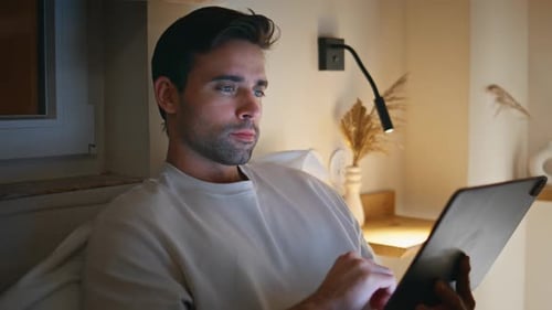 Man Using Tablet Device at Home in Evening Light