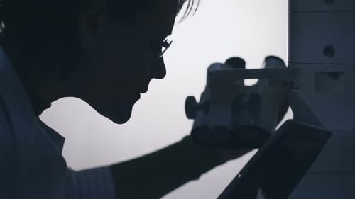 Woman Using Microscope in Science Lab