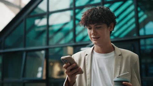 Portrait of Businessman with Coffee Cup Using Smartphone at Office Building