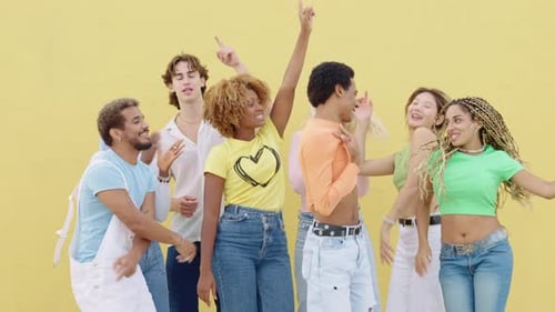 Friends Dancing Together in Front of Yellow Wall
