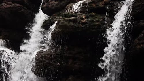 Small waterfalls cascading over rugged rocks, creating a serene, picturesque scene, shot in slow mot