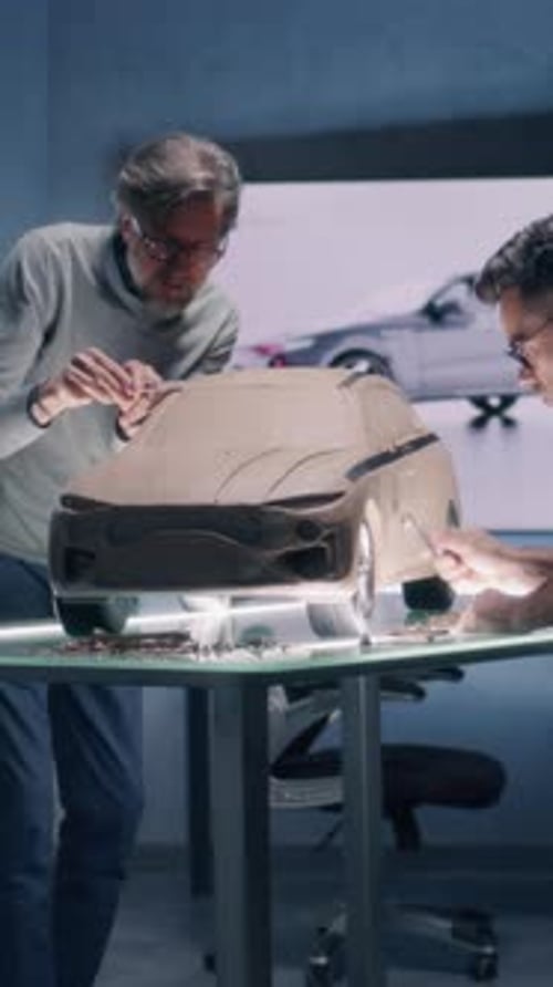 Designers masculins sculptant un modèle de voiture dans un atelier