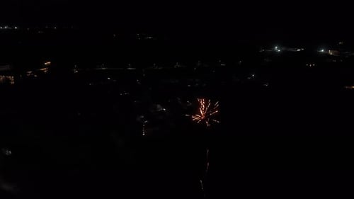 Aerial view of fireworks exploding over town at night
