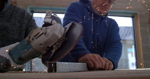 Construction Workers Cutting Metal with an Angle Grinder