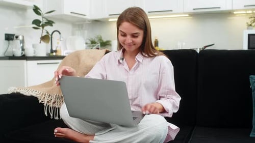 Woman Using Laptop on Couch in Bright Kitchen
