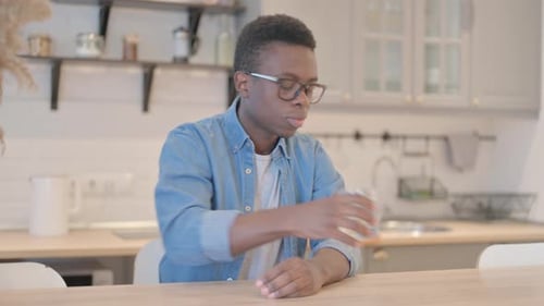 Young Man Drinking Water while Sitting at Home