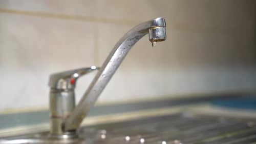 Water Dripping From Metal Faucet in Sink