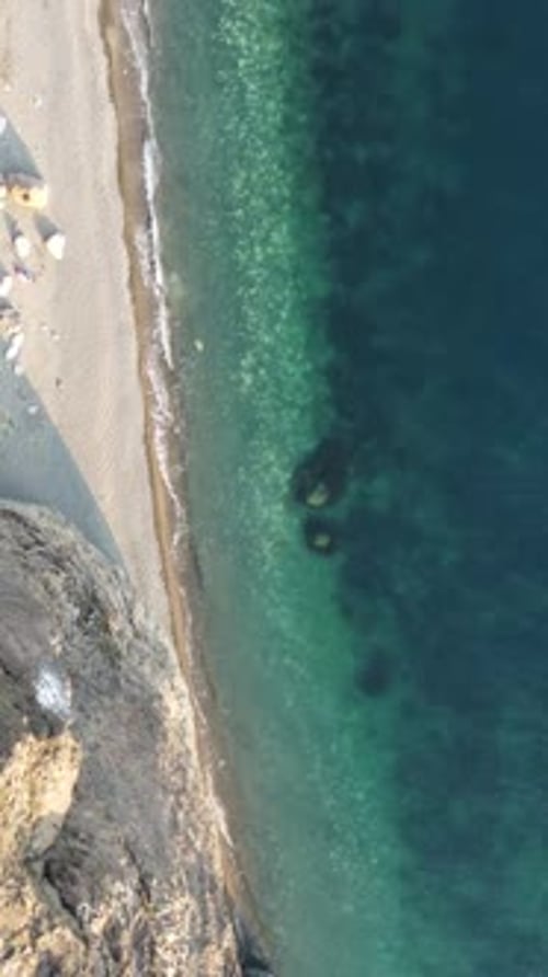 Aerial Vertical View of Beach with Wave Caressing Shore Sun Glare Small Waves on the Water Surface