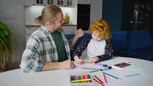 Junger Vater und rothaariger Junge im Vorschulalter zeichnen Bild