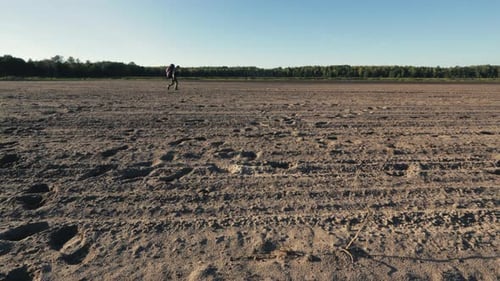 Traveler Walking Across Dry Rural Field on Sunny Day