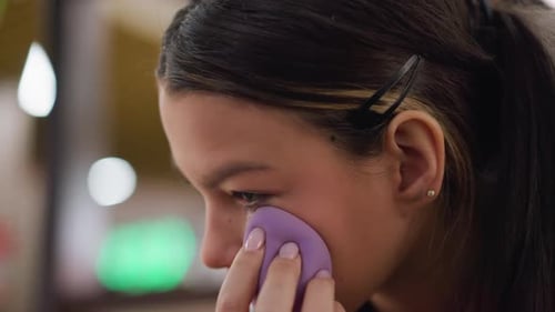 Closeup View of Woman Applying Powder with Makeup Sponge Under Eye