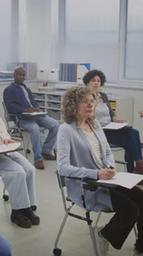 Adults Attending Class Taking Notes in Classroom