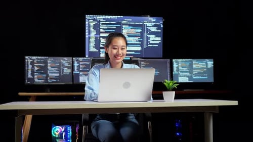 Une programmeuse entre dans l'espace de travail pour écrire du code à l'aide d'un ordinateur portable à l'aide de plusieurs moniteurs