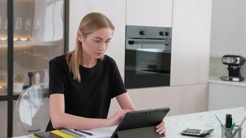 Woman Using Tablet Looks Stressed in Kitchen