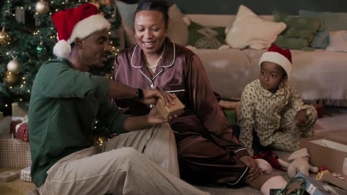 Family Unwrapping Christmas Gift Together at Home