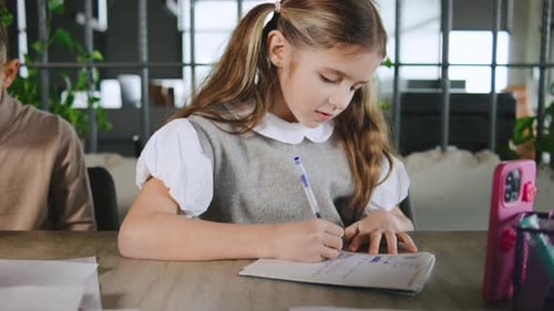 Young Girl Writing in Notebook at Desk