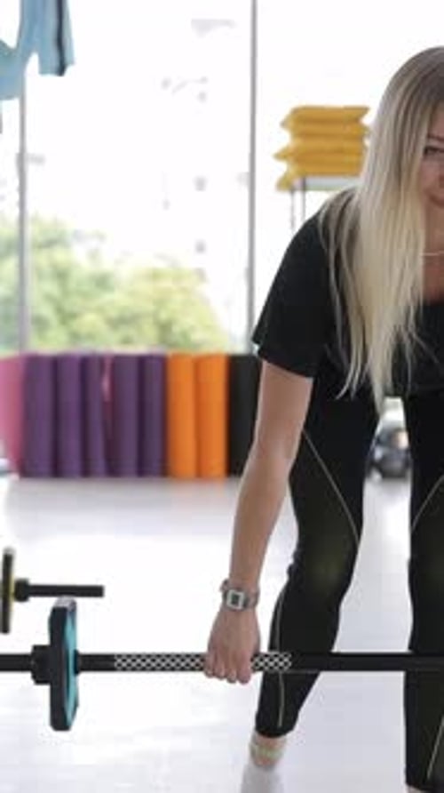 Active Women Squat with Dumbbells During a Workout in the Gym Vertical Video