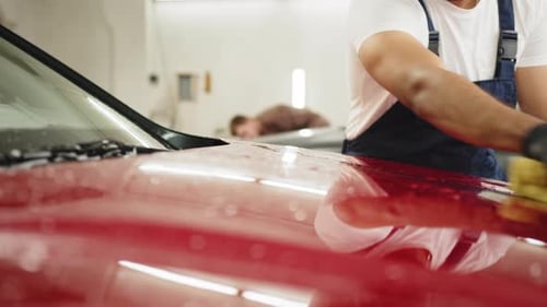 Confident Young Man Car Wash Worker Wearing Tshirt and Overalls Cleaning the