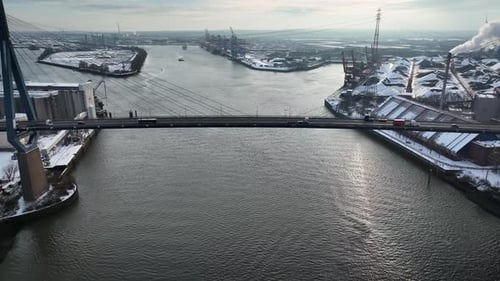 Aerial close-up of the Köhlbrand Bridge with vehicles moving across it. Large industrial harbor with