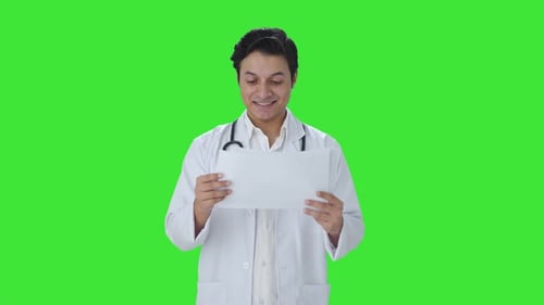 Happy Indian doctor checking medical reports Green screen