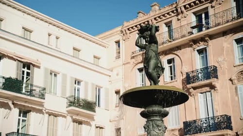 Close up view of a bronze fountain statue with flowing water, surrounded by classic architecture in
