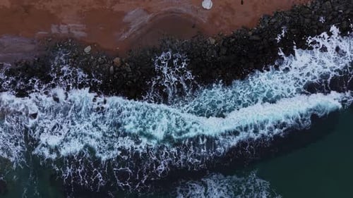 Waves crashing on rocky shore at sunset in coastal location