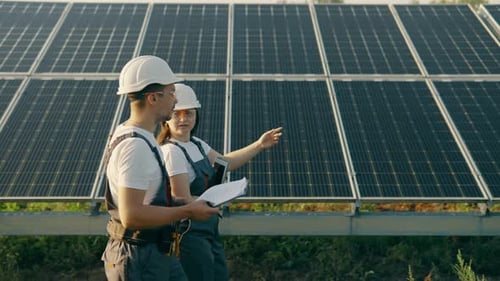 Workers in Overalls Walk Around the Solar Panel Area and Analyze Data