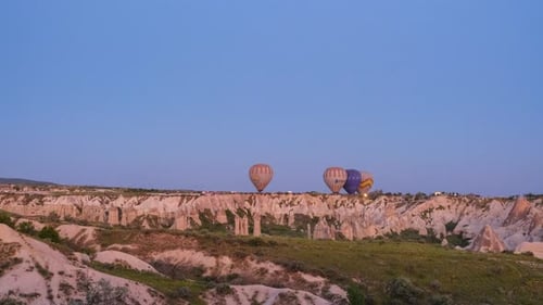 Timelapse shot of many colorful hot air balloons fly in the sky over a mountain valley at summer