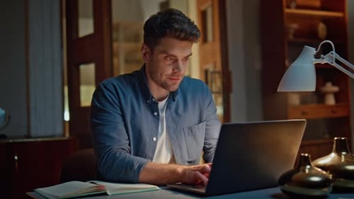 Young Adult Typing on Laptop at Desk Indoors
