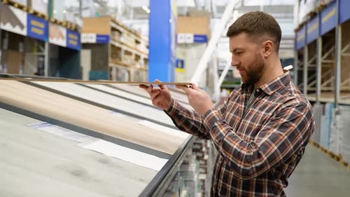 A Man Choosing Wood Laminated Flooring in Shop