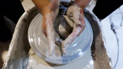 overhead close view of an African American hands spinning clay very sporadically