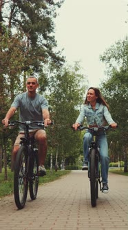Vertical Screen Couple Enjoying Joyful Bike Ride in the Park