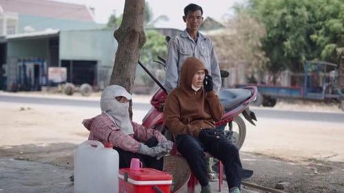 Group of Men and Women Chatting and Relaxing Resting Near the Road in Vietnam