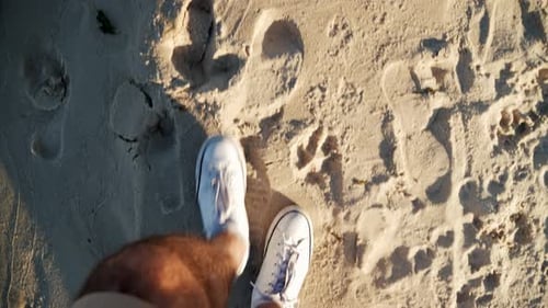 Legs in White Sneakers Walking Along the Beach Topdown View at Sunset