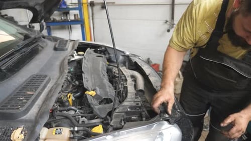 Mechanic Makes an Car Maintenance in Auto Service Professional Repairman Working Under Hood of