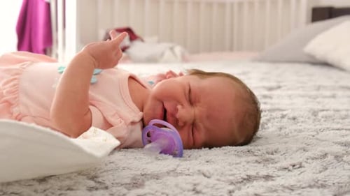 Infant Lying Down With Pacifier in a Bright Room