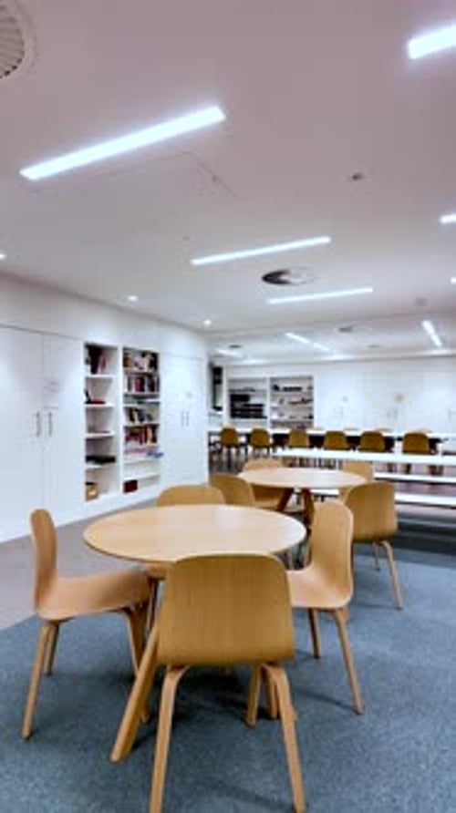 Modern Office Meeting Area With Empty Round Tables And Wooden Chairs White Walls And Shelves Nobody