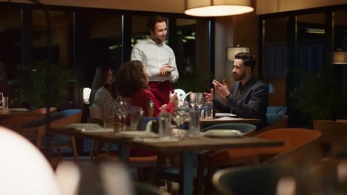 Waiter Serving Multiethnic Couple on Fancy Restaurant Dinner Date at Night. Two